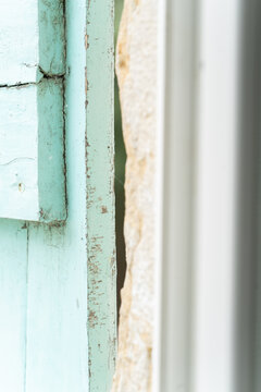 Minimalist close-up of weathered rustic mint green wooden shutter edge with chipped paint and stone wall