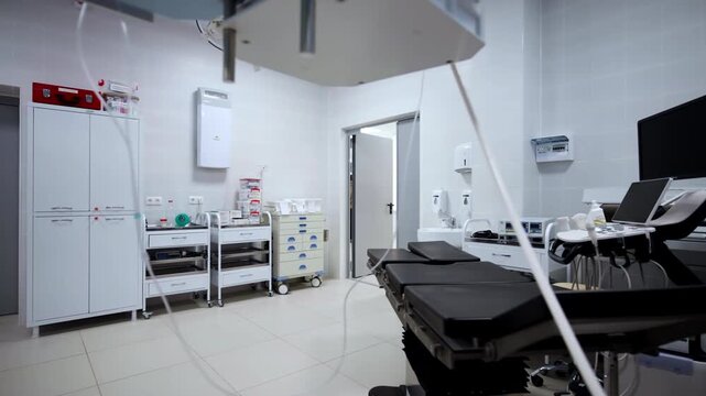 Medical room displays surgical couch under specialized lighting systems. Spotless workspace conveys sense of safety and precision