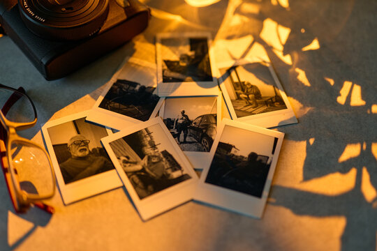 Old photos arranged on a table near a camera and a pair of glasses capturing memories and moments from the past