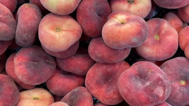 Flat peaches form a colorful background with vibrant red shades for summer freshness and texture
