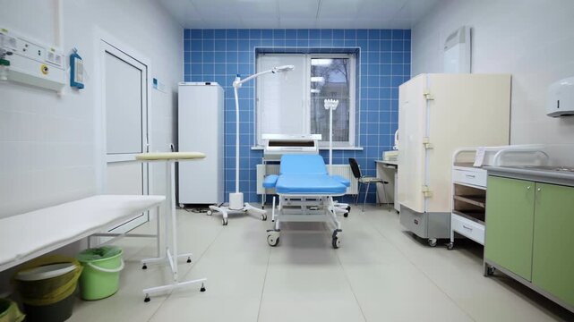 Medical treatment room features tiled wall adjustable procedure chair and equipment carts. Spotless interior creates highly secure mood