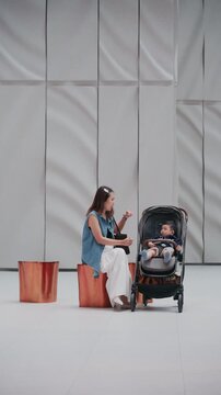Asian family mother and child with baby carriage in modern shopping mall hall.	

