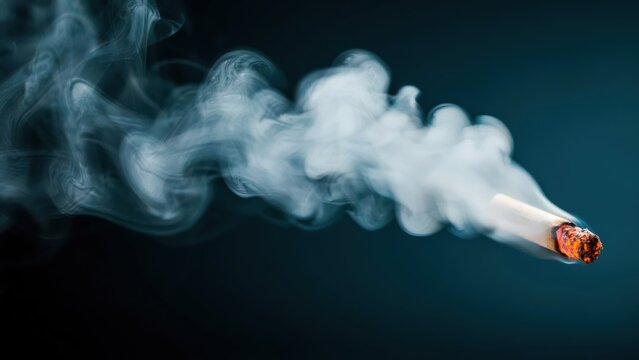 Lit cigarette releasing thick gray smoke on a dark background. Symbolizing health risks and the dangers of tobacco.