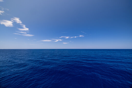 Inspire deep blue open sea bright sky soft clouds wide horizon. Minimal Mediterranean seascape travel wellness design. Calm ocean waters scenic wallpaper background copy space banner