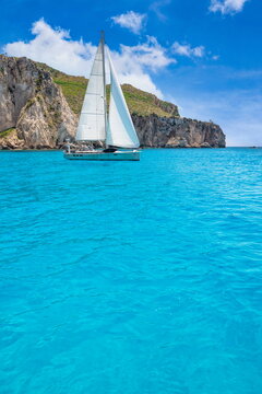 Adventure coastal cliff vivid turquoise sea idyllic sailboat clear sky. Dramatic Mediterranean seascape travel nature design. Aqua rocky coast headland scenic wallpaper vertical background copy space