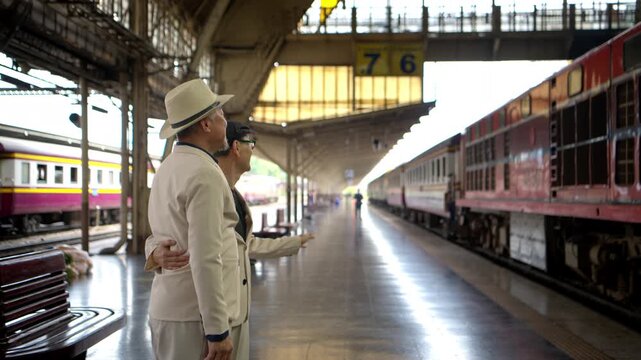 Happy senior LGBTQ couple met at Bangkok's old train station in Thailand for conversation, socializing, and a holiday