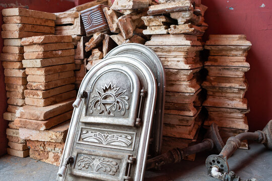 Antique Cast Iron Stove Door Among Stacked Clay Tiles