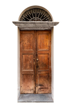 Old weathered double wooden door with a warm brown texture, featuring a classic arched stone lintel and a decorative black wrought iron security grille in the lunette above, isolated