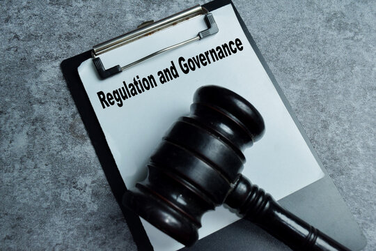 Concept of regulation and governance write on clipboard isolated on Wooden Table.