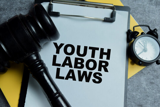 Concept of youth labor laws write on clipboard isolated on Wooden Table.
