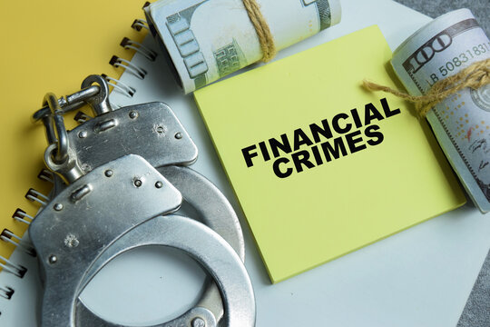Concept of financial crimes write on sticky notes isolated on Wooden Table.