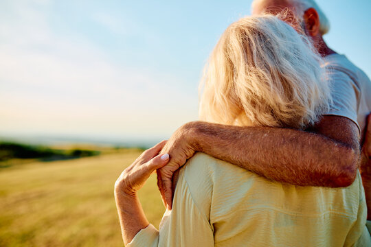 Senior couple embracing outdoors, symbolizing lasting love, support, and retirement together in golden hour light