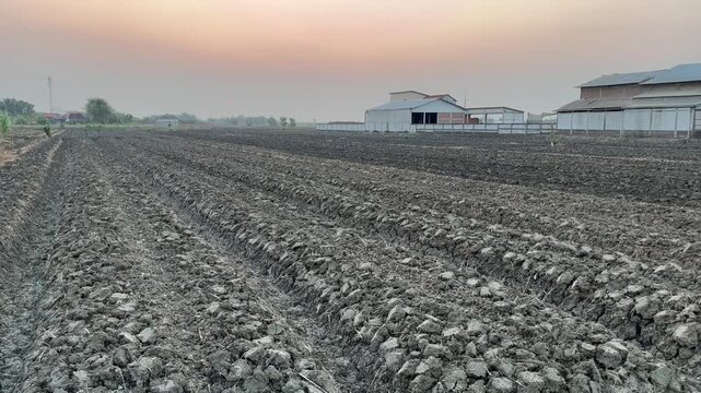 High angle view of plowed agricultural field and farm buildings