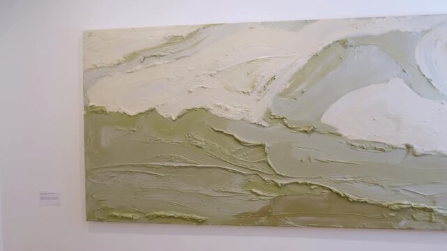 Slow frontal pan across textured abstract oil painting in gallery setting, showing thick impasto brushwork, palette knife ridges, muted sage, olive, beige, off white tones