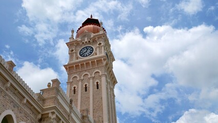 Obraz premium Sultan Abdul Samad Building clock tower featuring Moorish architecture set against a blue sky with white clouds.
