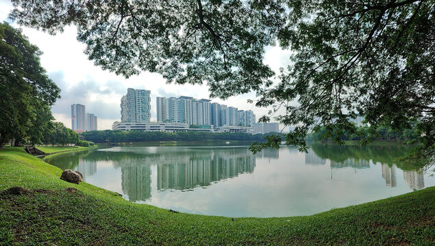 Panorama View of Urban Lake Reflecting Modern Residential Buildings Framed by Tree Canopy at Taman Tasik Danau Kota, Kuala Lumpur, Malaysia