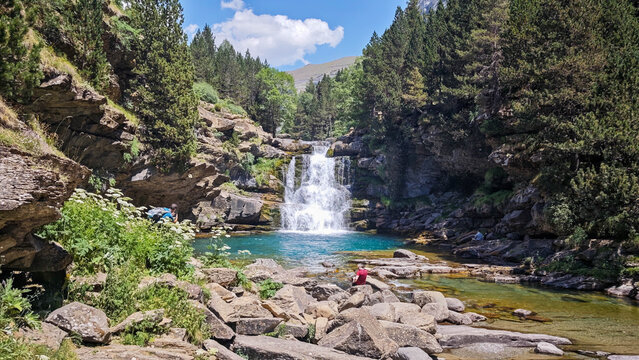Wide angle horizontal view of a scenic waterfall and turquoise pool in Ordesa.