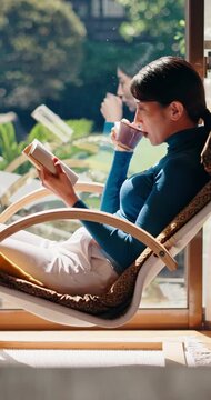 Relax, reading book and Asian woman with tea in home, fiction story or tale on weekend break. Japanese person, drink and novel in house for fantasy, chill and literature hobby with chapter on chair