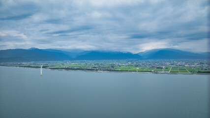 Fototapeta premium 梅雨明け前で高気温、高湿度の富山県下新川海岸の洋上風力発電風車や笹川地区や、さらに東側の糸魚川市の山の様子など