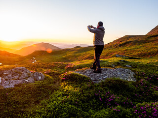 Obraz premium Hiker Photographing Sunrise With Smartphone in Rodnei Mountains