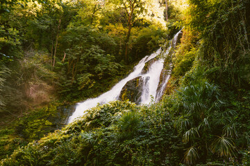 Picturesque cascade glowing beneath tall canyon walls in summer at Bellano © Jan Cattaneo