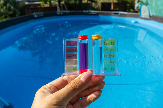 Hand Holding Water Quality Tester Kit Above Blue Swimming Pool