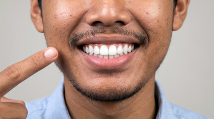 Fototapeta premium Close up of man pointing at healthy white teeth