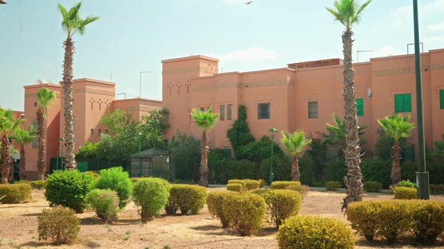 Sunlit Moroccan-Style Pink Buildings and Palm Garden With Terracotta Walls and Green Shutters
