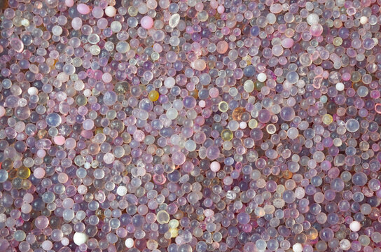 Close up full frame background texture of colorful purple and pink silica gel desiccant beads.