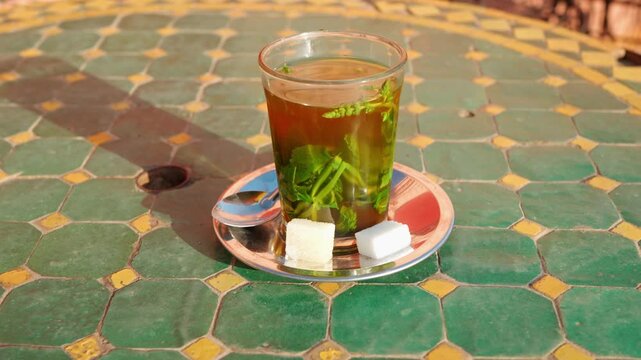 Refreshing Moroccan Mint Tea In Glass On Decorative Tiled Table With Sugar Cubes And Spoon