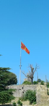 Flagge Nordmazedoniens auf einem hohen Mast an einer historischen Festungsmauer