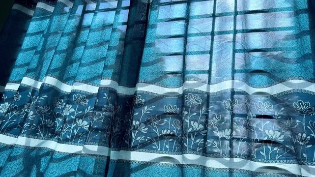 Sunlight Filtering Through Blue Floral Patterned Window Curtain