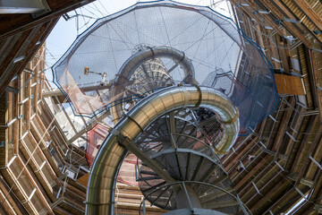 Fototapeta premium view from the bottom up to the top inside of the Treetop Walkway (Stezka korunami stromu) in sunny day Lipno nad Vltavou, South Bohemia, Czech Republic. In the middle, there is a spiral metal slide.