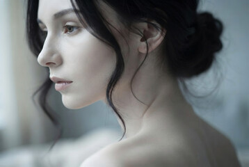 Fototapeta premium Soft profile portrait of young brunette woman with natural skin and minimal makeup in gentle daylight