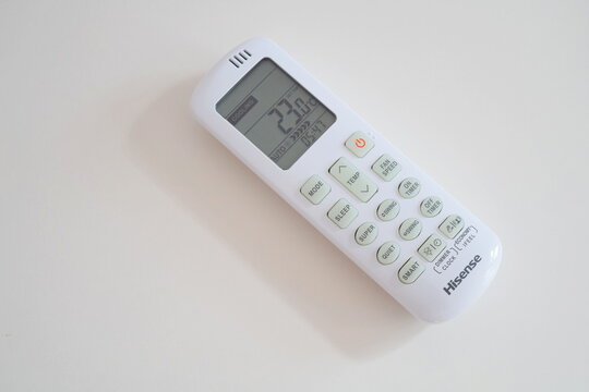 Hisense white air conditioner remote control lying on light background with display showing cooling mode and temperature