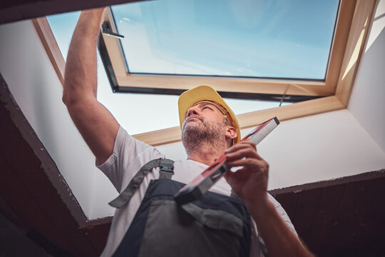 Carpenter installing roof windows in the attic.
