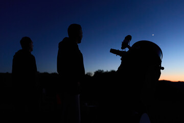 Amateur astronomers observing stars, planets, Moon and other celestial objects with a telescope in nature. © astrosystem