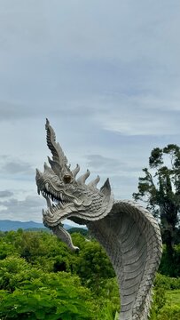 Traditional carved stone naga dragon sculpture against a bright blue sky at an Asian temple