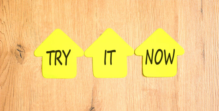Try it now words symbol. Concept words Try is now on beautiful yellow paper houses. Beautiful wooden background. Business support motivational and try is now concept. Copy space.