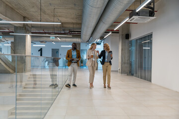 Fototapeta premium Business team holds coffee cups while walking in modern office space