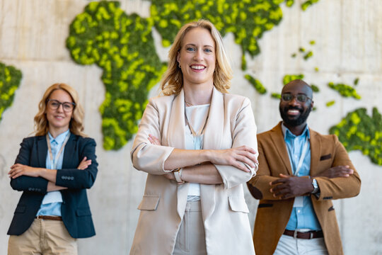 Business team stands together in office with a world map behind them in a modern setting
