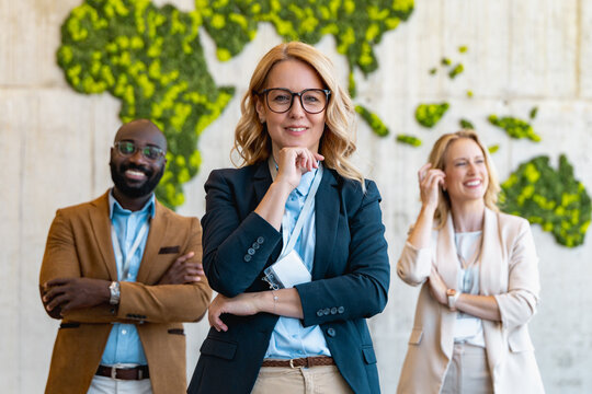 Business team poses confidently in front of a world map made of greenery in a modern office setting