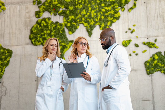 Medical professionals discuss patient care in a health facility with a green wall map