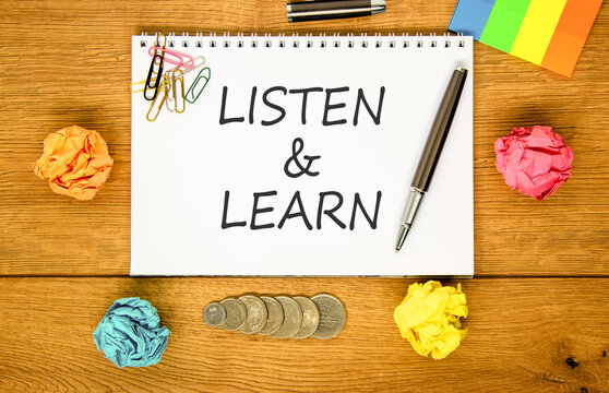 Listen and learn words symbol. Concept words Listen and learn on beautiful white note. Beautiful wooden background. Black pen. Colored paper. Business listen and learn support concept. Copy space.