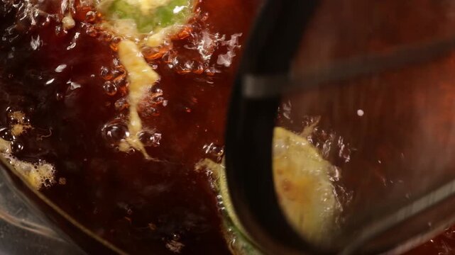 Deep frying battered eggplant and acacia pennata omelet slices in hot oil pan for spicy shrimp paste dip at Bangkok.
