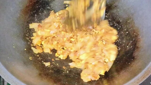 Chef stir frying flat rice noodles kwetiau with scrambled egg in wok close up