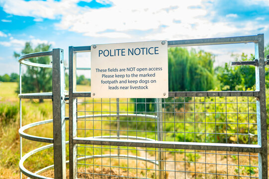 Shallow focus of a Sign at the entrance to a rural livestock farm field in the UK. The sign warns dog owners to keep them on a leash as to not endanger the livestock.