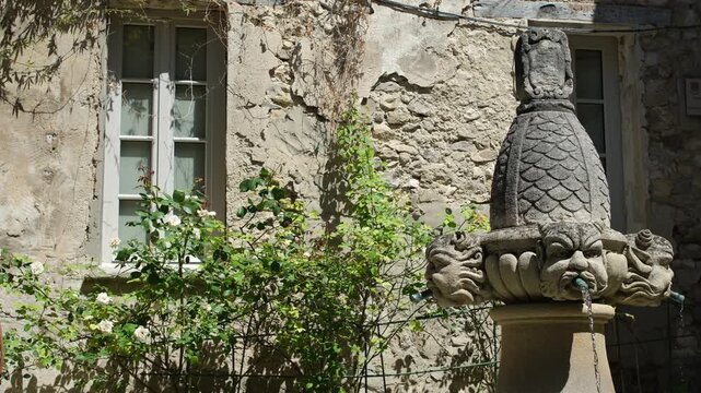 S&eacute;guret, Vaucluse, Provence-Alpes-C&ocirc;te d'Azur, France. July 04, 2026. Ancient Fountain of Mascarons surrounded by roses near village house. Cultural heritage.