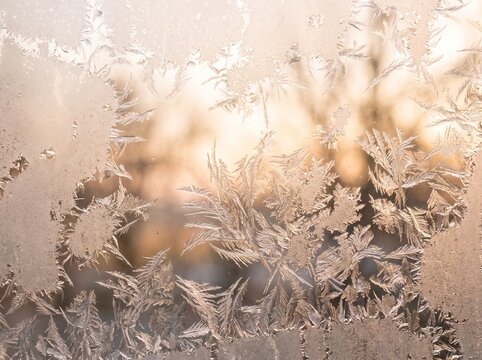 Frost patterns on a cold window with soft light.
