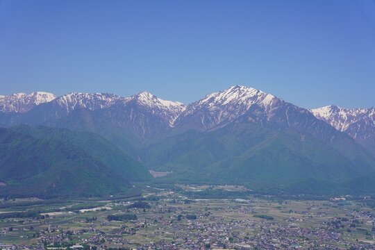 北アルプス　鷹狩山から望む残雪の北アルプスと新緑の大町市街　蓮華岳　北葛岳